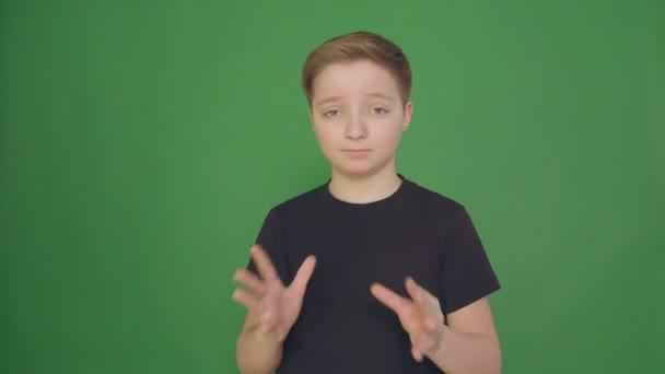 Piękny chłopak pokazuje różne emocje na zielonym tle. Kamery w rozdzielczości 4k. Film w zwolnionym tempie. — Wideo stockowe