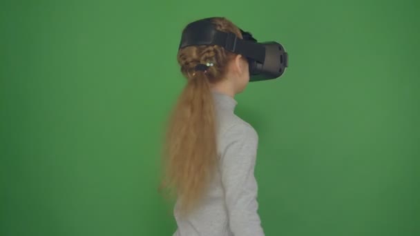 Video de alta calidad de niño con gafas de realidad virtual. Chica feliz merodeando en gafas de realidad virtual. Niña en un fondo verde, cámara en 4K . — Vídeos de Stock