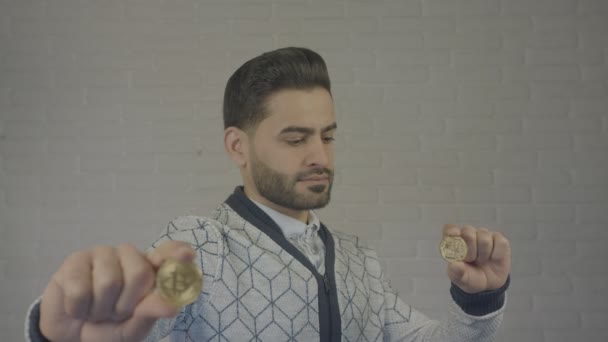 Retrato de homem segurando bitcoin em sua mão. Ele está a olhar para a moeda . — Vídeo de Stock