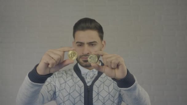 Portrait de l'homme tenant Bitcoin dans sa main. Il regarde la pièce . — Video