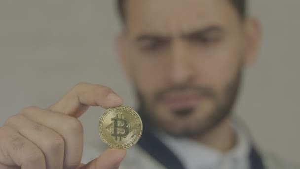 彼の手を抱きかかえた bitcoin の肖像画。彼はコインを探しています。白い背景の上の若い男. — ストック動画