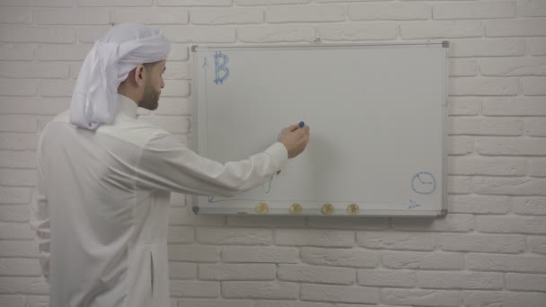 Арабські людина звертає діаграми і показує за bitcoin. Bitcoin є cryptocurrency по всьому світу і цифрових платіжної системи. — стокове відео