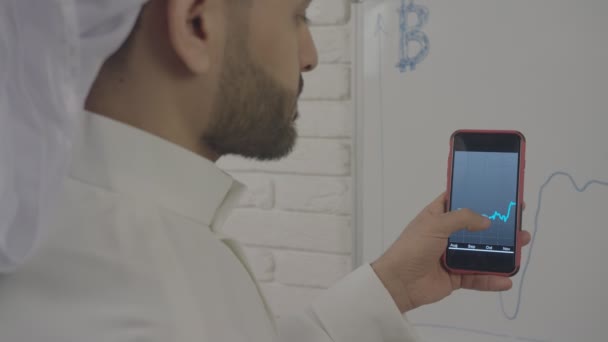 職場で男は、スマート フォンの bitcoin 財布を使用します。電話で手のフレームで、男が誰かアドレスに、bitcoins を送信します。. — ストック動画