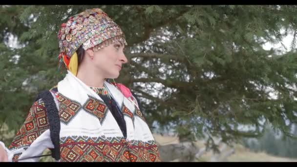 Feliz pareja joven en trajes nacionales bordados caminar en el campo. Boda ucraniana en ropa tradicional — Vídeos de Stock
