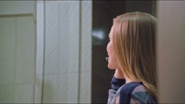 Güzel bir kadın banyoda dişlerini fırçalıyor, aynaya bakıyor, ağız temizliğinin tadını çıkarıyor, sabahları kayak yapmaya hazırlanıyor.