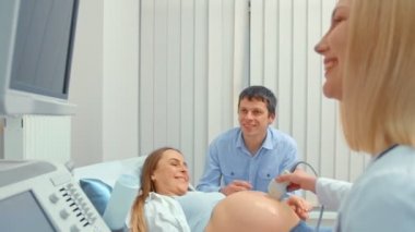 Kanepedeki tablette bebeğin ultrason taramasına bakan çift.