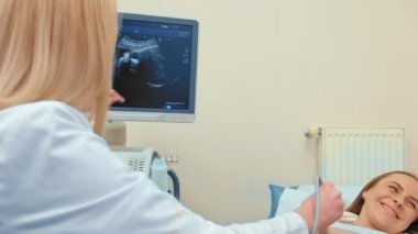 Ultrasonografi süreci, doktorun bebeği mutlu hamile kadının karnında kontrol etmesi, modern tıp teknolojisi.