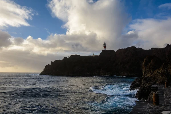 Gün batımında deniz feneri. Deniz feneri güzel bir şekilde yüksek kayalarda duruyor.. — Stok fotoğraf