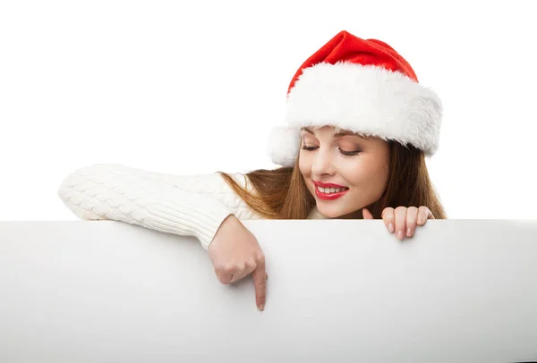 Weihnachtsfrau mit Weihnachtsmütze zeigt auf leeres Brett — Stockfoto