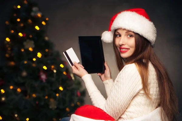 Mujer sentada con tablet PC y tarjeta sobre árbol de Navidad —  Fotos de Stock