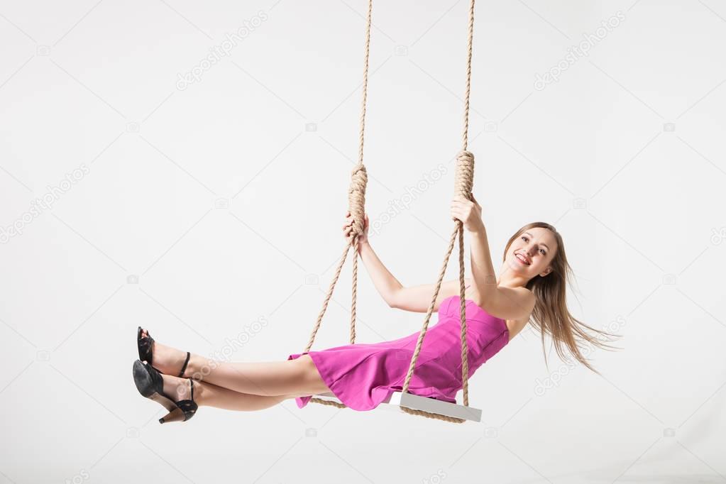 beautiful blond woman on swing against white