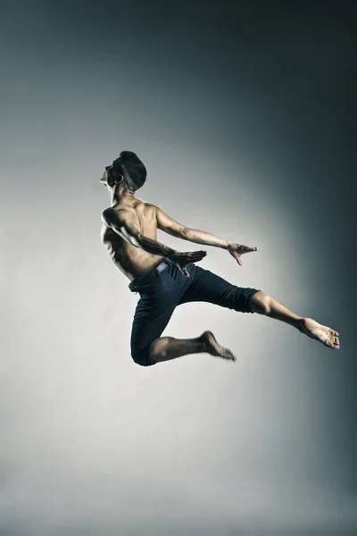 Caucasian man gymnastic leap posture on grey — Stock Photo, Image