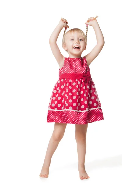 Roztomilý usměvavá holčička v červených šatech, které vystupují ve studiu — Stock fotografie