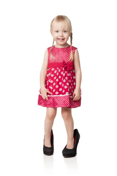 Smiling little girl wearing big shoes — Stock Photo, Image