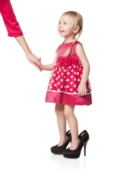 Sonriente niña pequeña usando grandes zapatos kipping mano de su madre — Foto de Stock