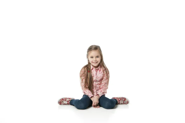 Pretty little girl sitting on the floor in jeans — Stock Photo, Image