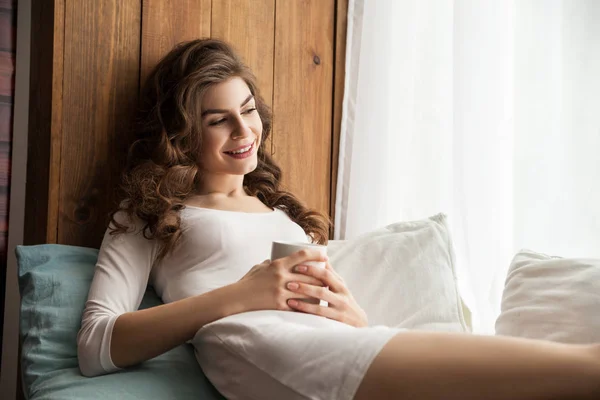 Smiling female lying with the cup — Stock Photo, Image