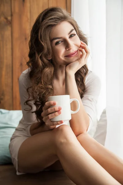 Улыбающаяся молодая женщина с чашкой — стоковое фото