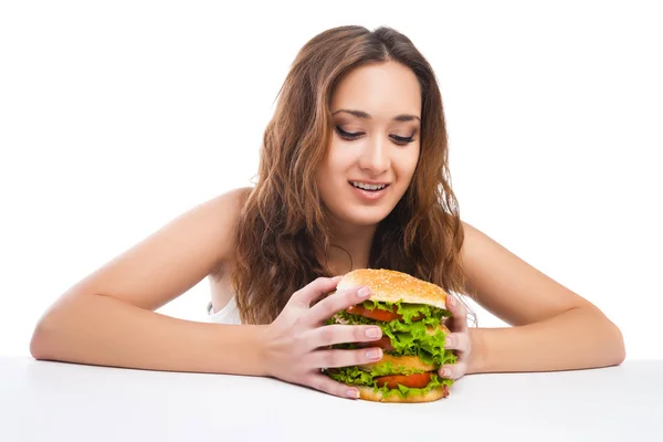 Szczęśliwa młoda kobieta jedzenie pyszne burger duży na białym tle — Zdjęcie stockowe