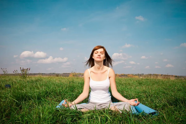 Ung flicka gör lotus yogaställning i parken — Stockfoto