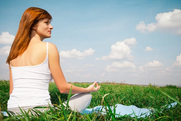 Ung flicka gör lotus yogaställning i parken — Stockfoto