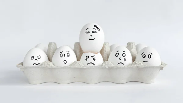 Eggs with funny faces in the package on a white background. Easter Concept Photo. Faces on the eggs