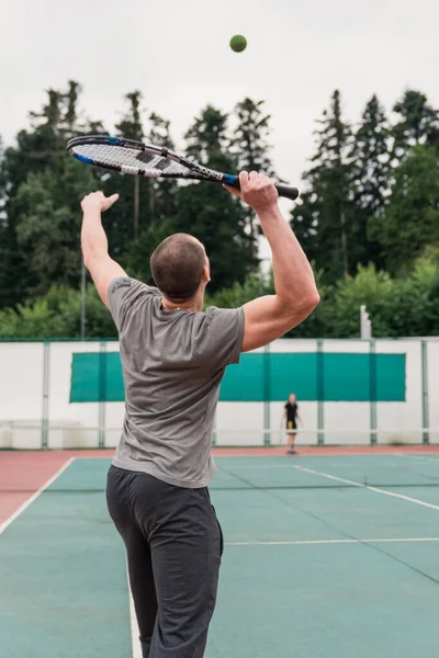 テニスをしながらボールに仕える男の後ろ姿 晴れた日に屋外でテニスをする男性 ストック画像