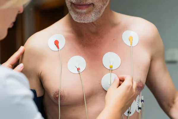 心臓診断検査中の老人 胸に女性の手を入れる検出器 ストック画像
