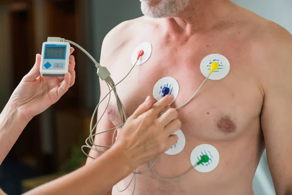 心臓診断検査中の老人 女性の手は胸に検出器を置き 工夫で測定します ロイヤリティフリーのストック画像