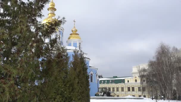 キエフ聖ミハイルの黄金ドーム大聖堂冬 建物の前に雪 大聖堂の前に針葉樹 トラクターをきれいに雪からの道 — ストック動画