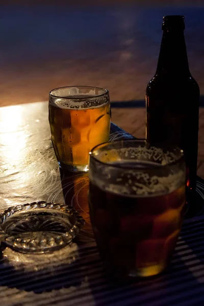 Beer in a glass, a bottle and an ashtray on the table — Stock Photo, Image