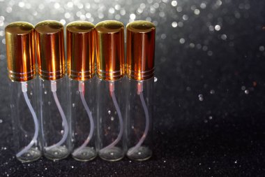 Koyu parlak arka planda beş cam uzunluğunda parfüm atomları. Pe