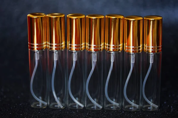 Seven transparent high perfume atomizers on a dark shiny backgro — Stock Photo, Image