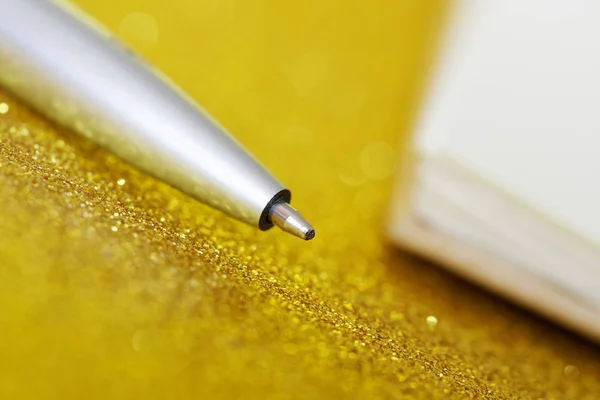 Egy ezüst töltőtoll fekszik egy arany háttér mellett egy jegyzet — Stock Fotó