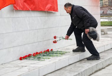 Yaşlı bir komünist muhalif ayaklarının dibine çiçek bırakıyor.