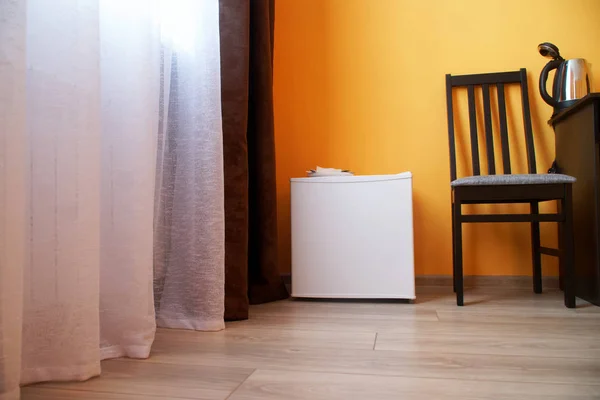 Small compact white refrigerator in the interior of a cramped st