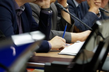 Not defterleri, kalemler ve saatlerle yapılan bir iş toplantısına katılanlar