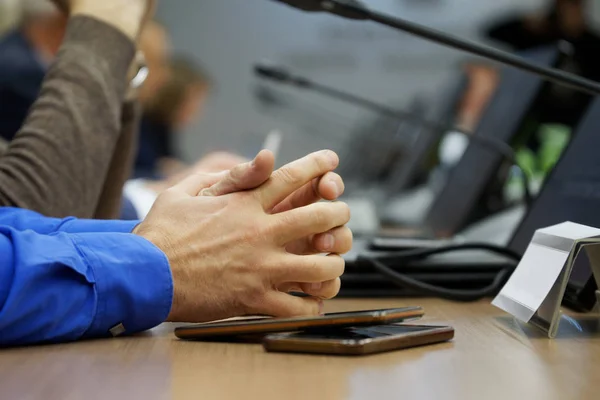 Hands of a man with crossed fingers during a meeting or negotiat
