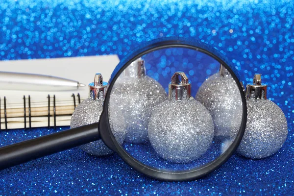Glanzende kerstballen naast een vergrootglas, notitieboekje en fontein — Stockfoto