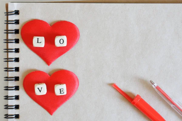 The word love and two red silk hearts, together with a fountain — Stock Photo, Image