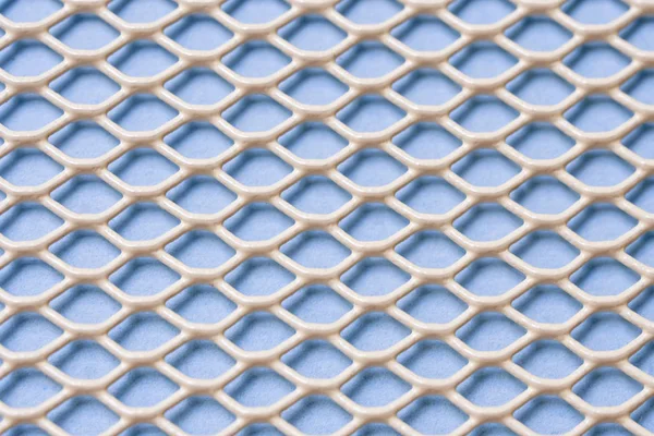 Vit metall nät med små celler på en blå bakgrund. Närbild — Stockfoto