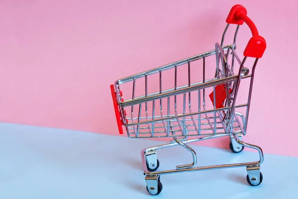 Supermarket metal trolley on light blue and pink background. Clo — 스톡 사진