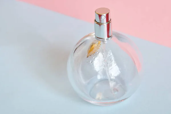 Przezroczysta okrągła pusta butelka perfum na różowym i niebieskim woreczku — Zdjęcie stockowe