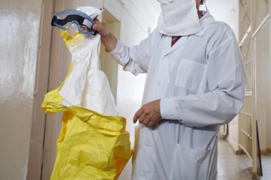 Beyaz önlüklü bir doktor, salgın ve salgın hastalıklar için sarı koruyucu elbise ve gözlük takıyor. Hastanenin koridoru. Yüzü olmayan. Sağlık konuları               
