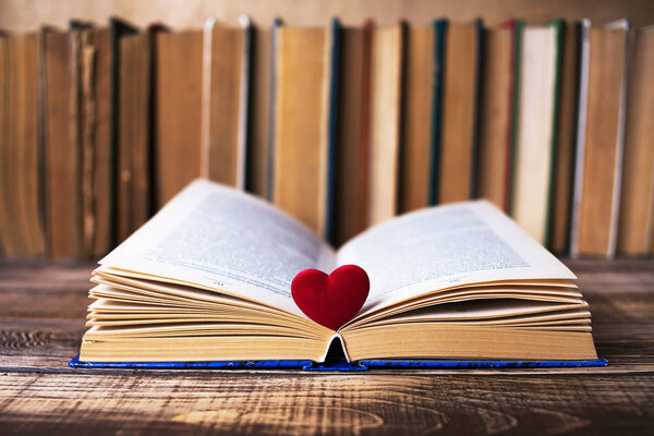 Books on the wooden table with red heart