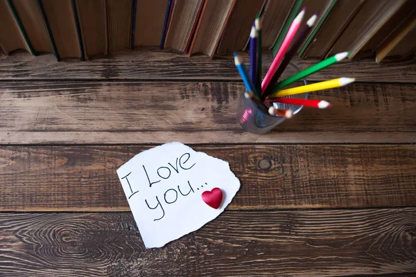 Libros en la mesa de madera, una nota con corazón, lápices de colores — Foto de Stock