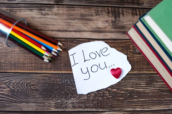 Libros en la mesa de madera, una nota con corazón, lápices de colores — Foto de Stock