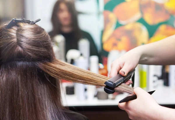 Hairdresser straightening long brown hair Royalty Free Stock Images