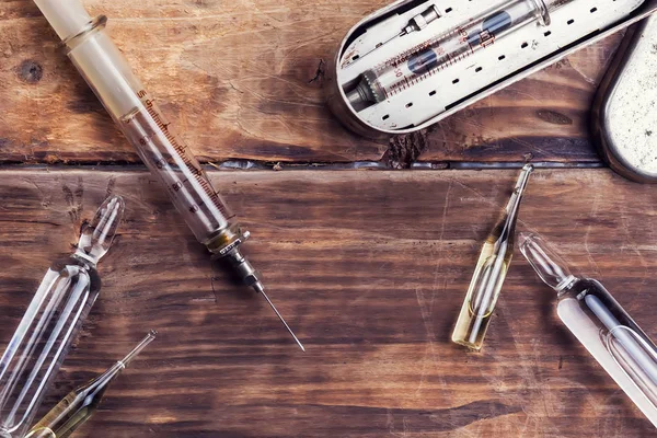 Uma seringa e ampolas de medicamento na mesa de madeira — Fotografia de Stock