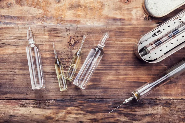 Uma seringa e ampolas de medicamento na mesa de madeira — Fotografia de Stock